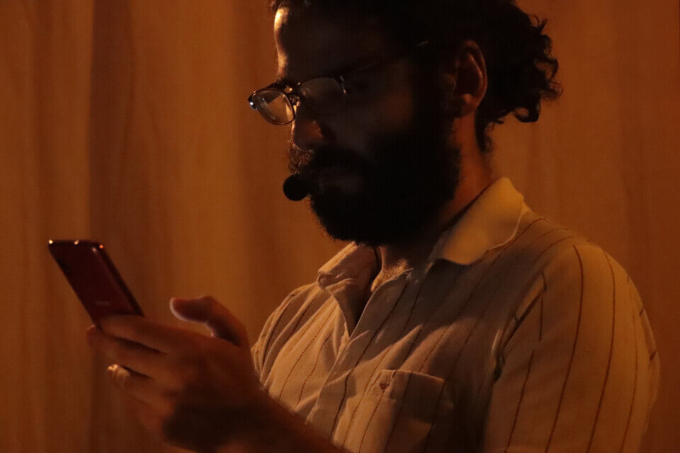 The performer holds and looks at his phone