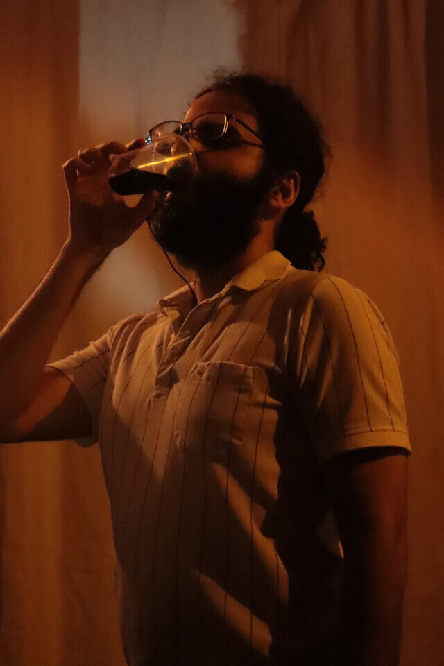 The performer drinks a glass of wine