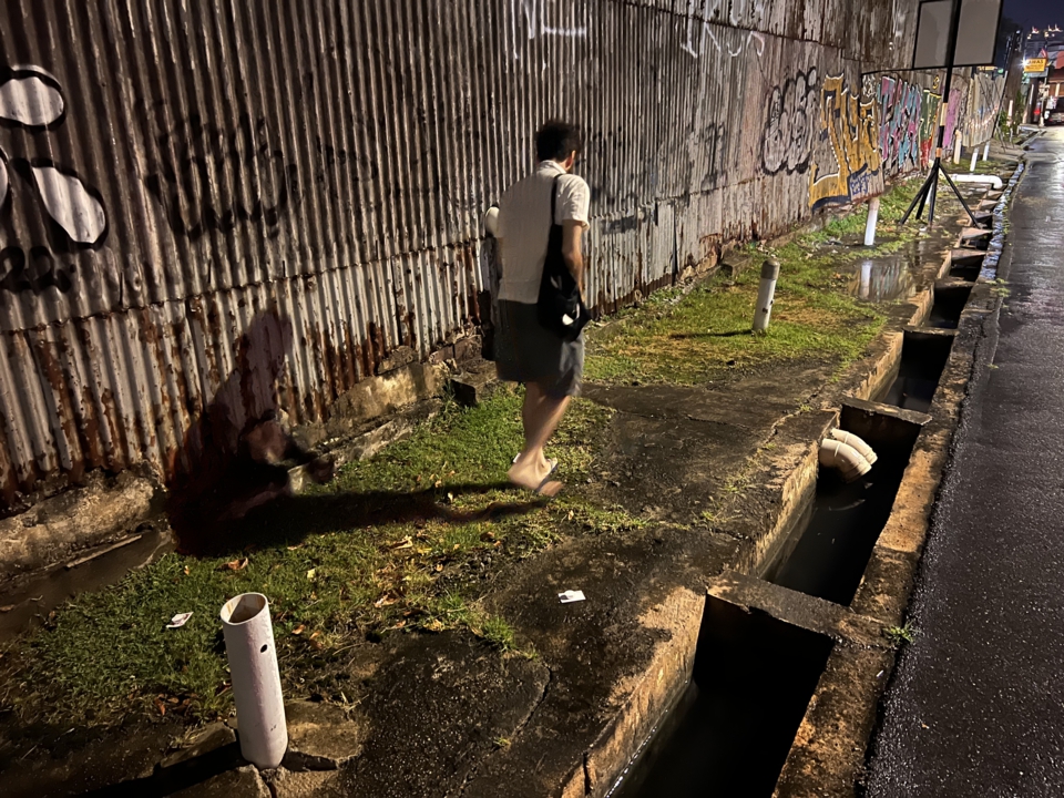 the artist walks along the grassy cement path. Behind him are two cards, already placed on the ground with candles on them