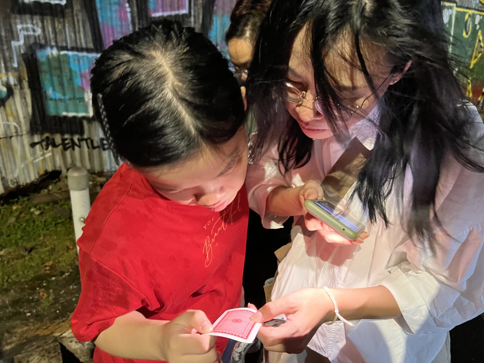 two of the same members examine the card by phone light