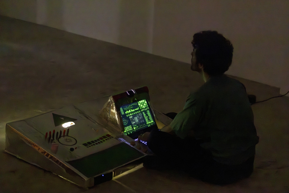 the artist can be seen manning a spaceship console in the dark. The screen of the console shows some analytical data.