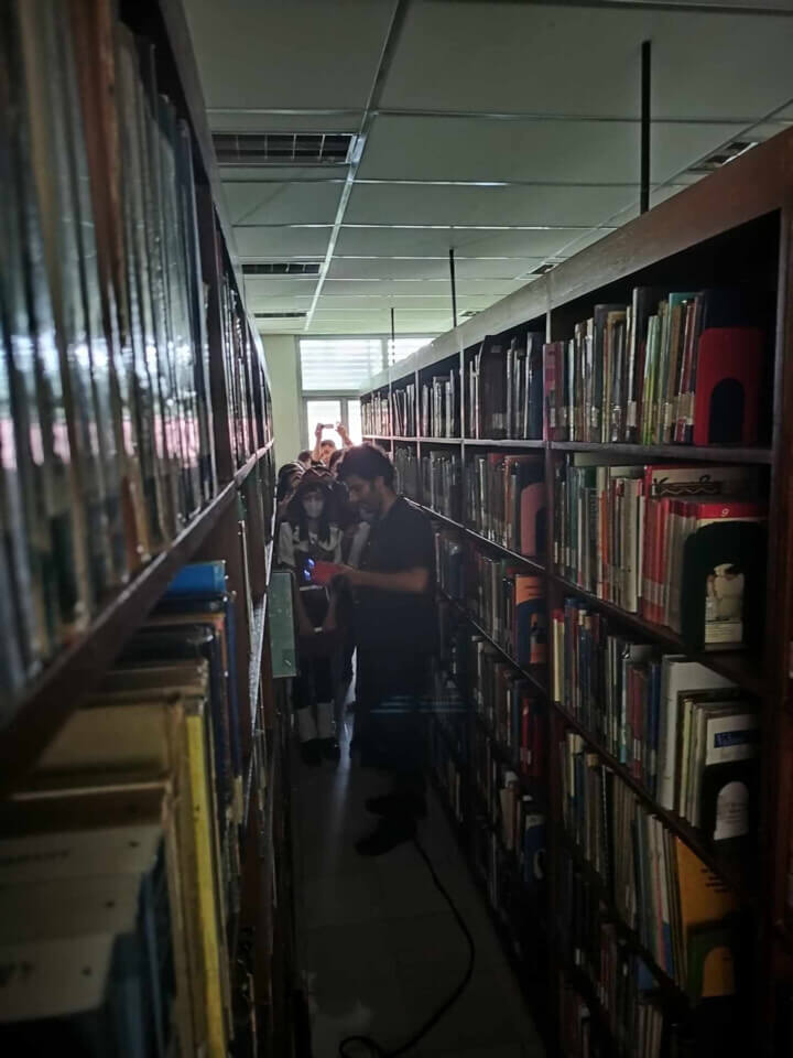 The students and other event guests are in the aisle with the performer as he looks at a book