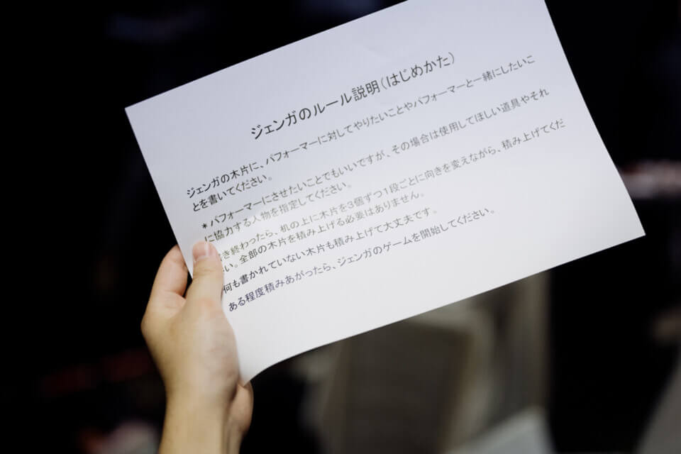 a hand holds the explanation for the jenga game in Japanese