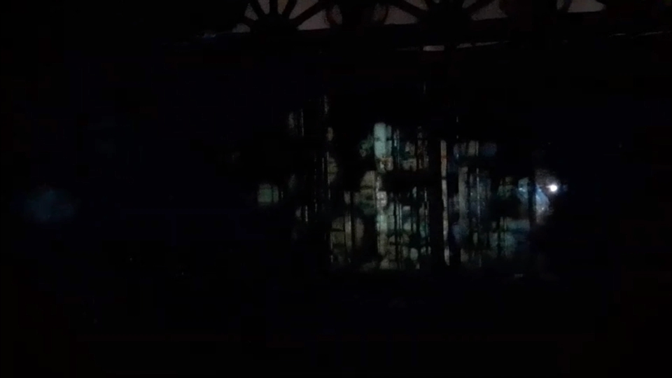 faces float on the closed window shutters of the bedroom. The faces are also reflecting off of the window glass and can be seen faintly reflected on the perpendicular wall.