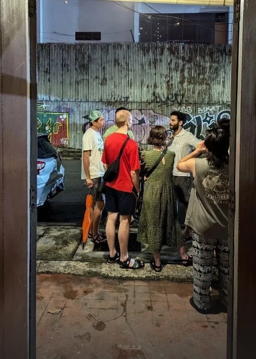 the artist discusses with some of the event visitors in front of the house entrance
