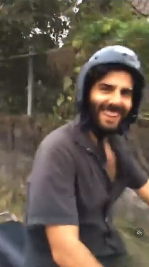 shot taken from the side of stephan while driving. He looks towards the camera, smiling